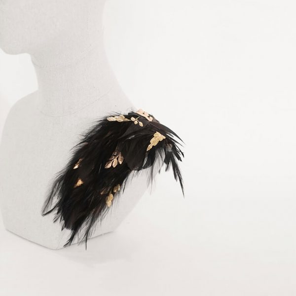 hombrera de plumas negras con detalles de hojas doradas y pedrería
