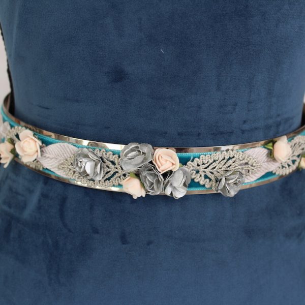 cinturón metálico plateado con tercipelo turquesa y decorado con flores.